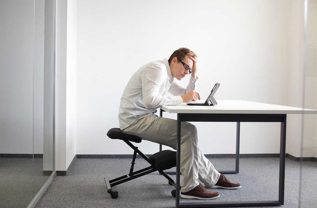 A young man bending over a tablet in his office.
