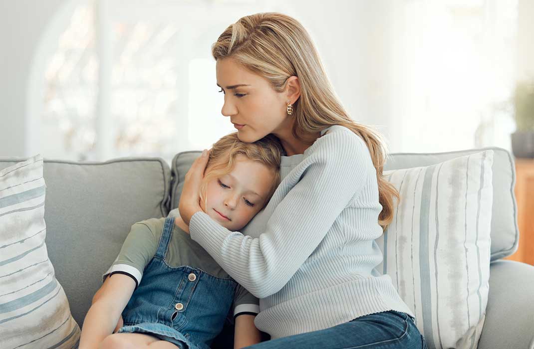 A mother hugs her young daughter.