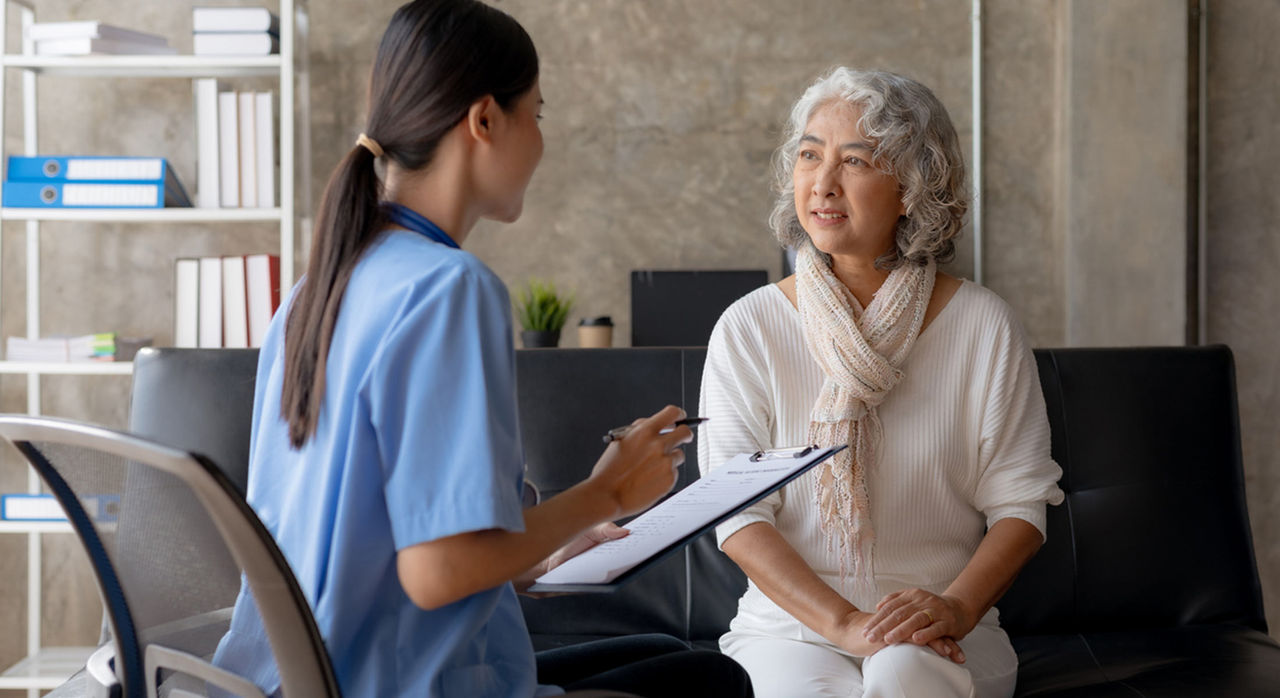 Nurse holds a clipboard and speaks with patient about treatment plan