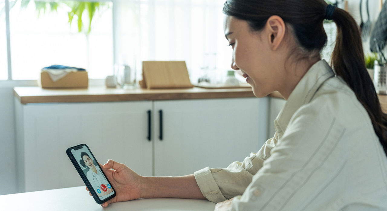 A woman speaks with a doctor about a yeast infection on a virtual urgent care visit via mobile phone.