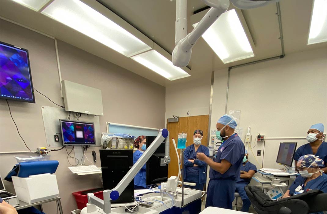 Several medical staff gathered in a room with equipment and monitors