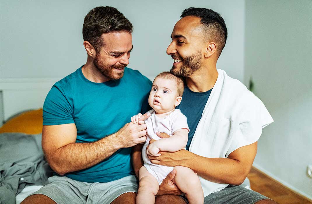 Two fathers holding their baby.