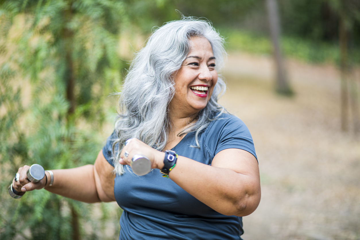 A woman with obesity uses weights outdoors