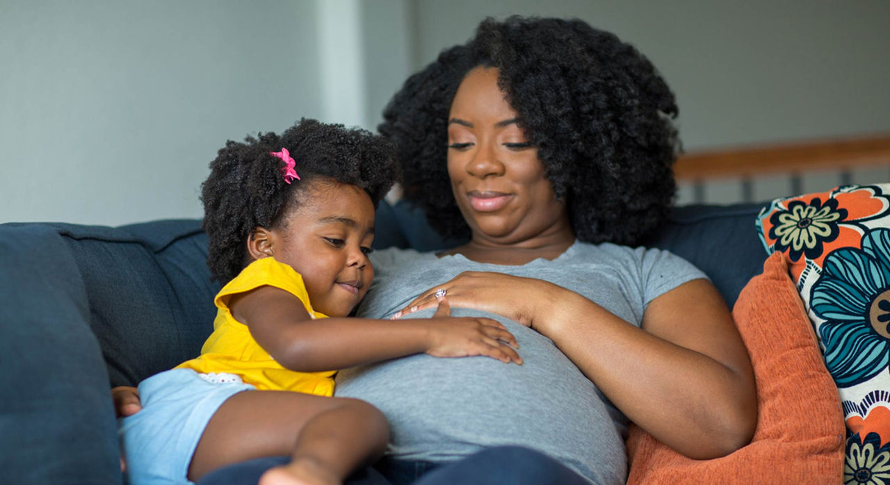 Pregnant woman hugging her child on a couch