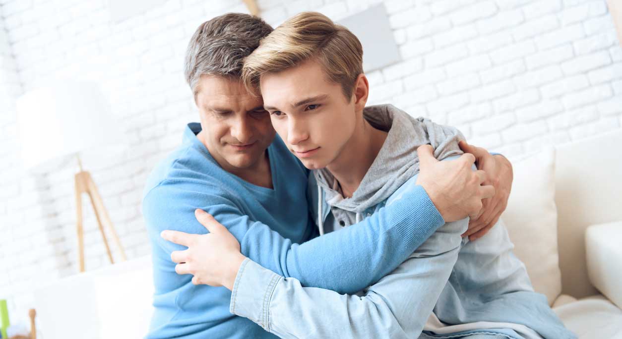Father and teenaged son embrace during a discussion.