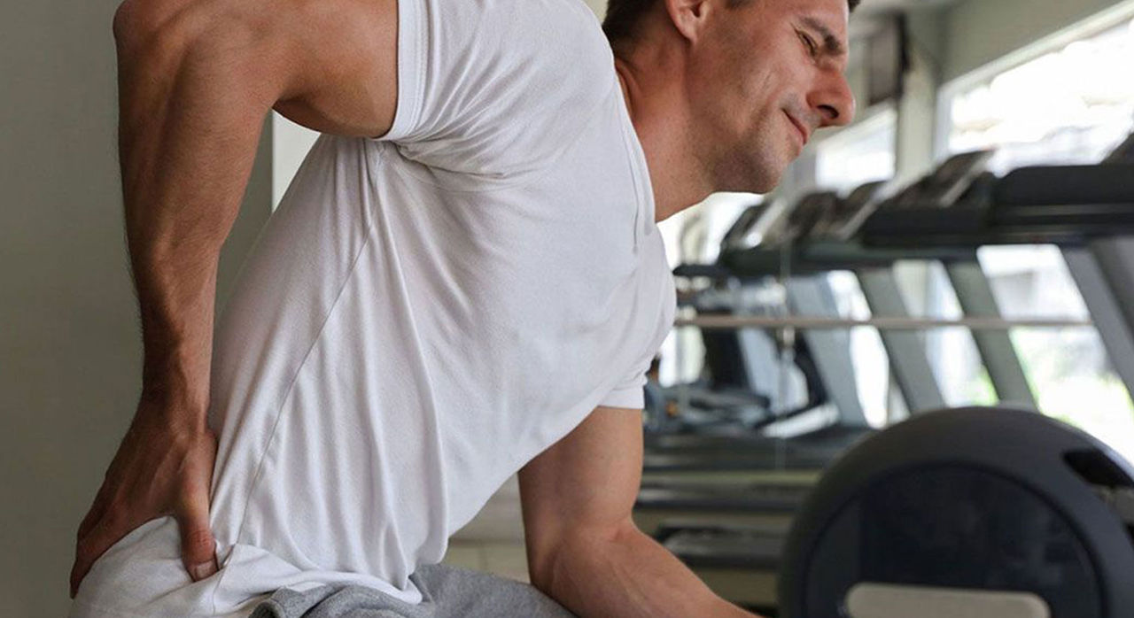 man experiencing muscle pain after workout at the gym