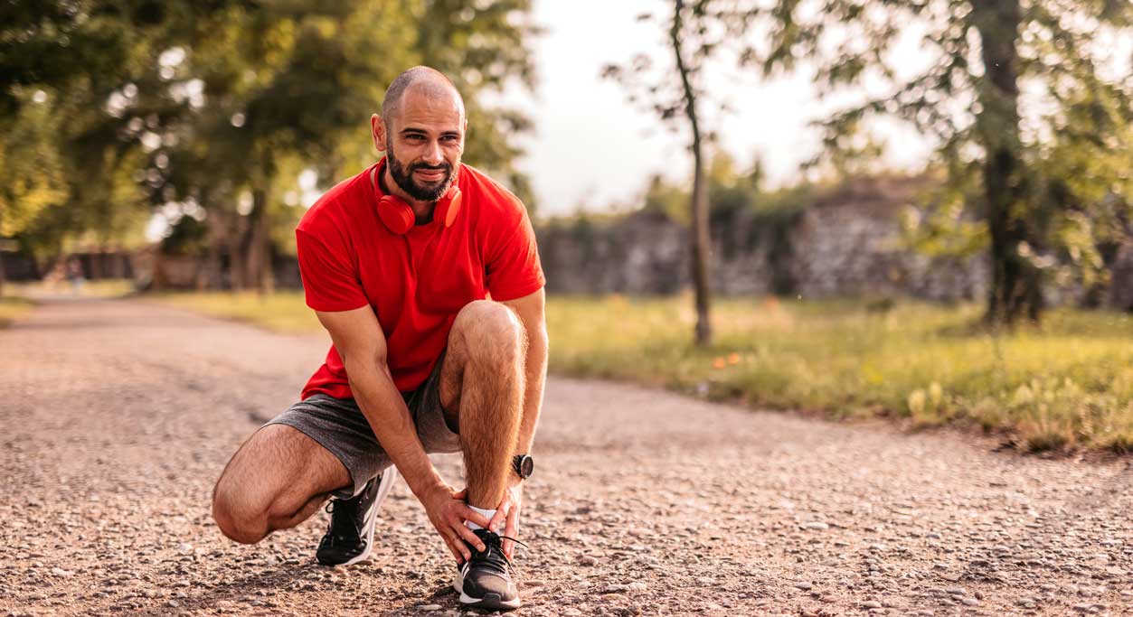 A runner on a paved path tends to his ankle.