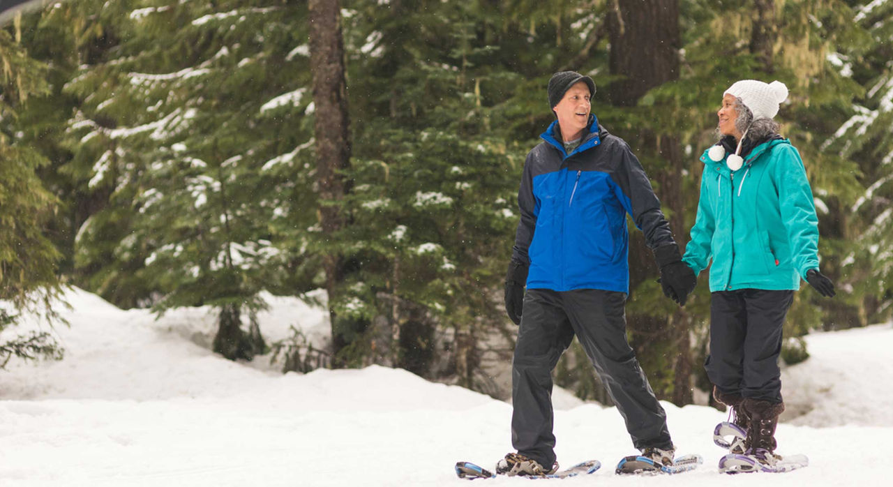A man and woman snowshoeing in the woods