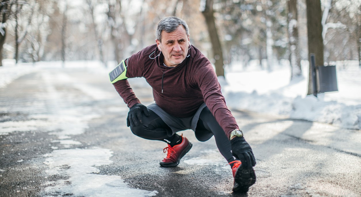 A jogger stretches before a run on a wintry road.