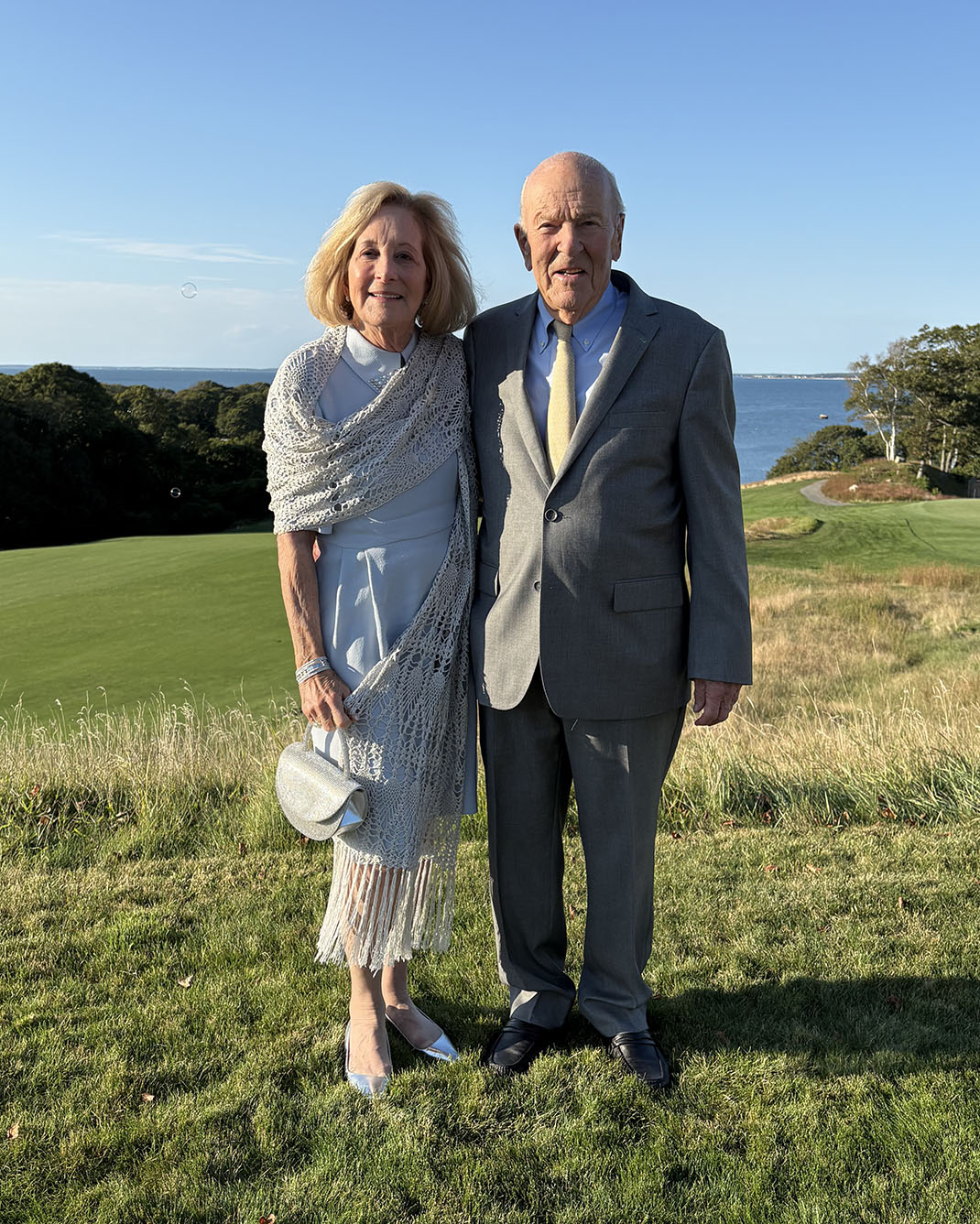 Senior man and women standing in a field near the ocean