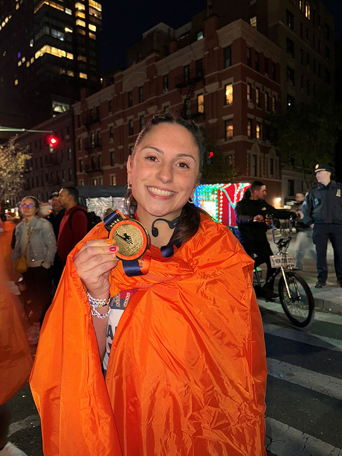 Alexa Hassan holds up her medal after a marathon.
