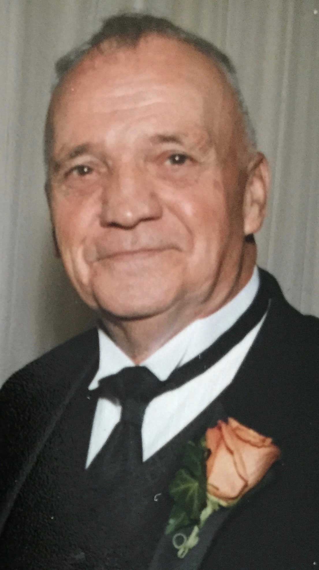 Bill Hanafin, an elderly white man in a sharp black suit with a rose in his breast pocket.