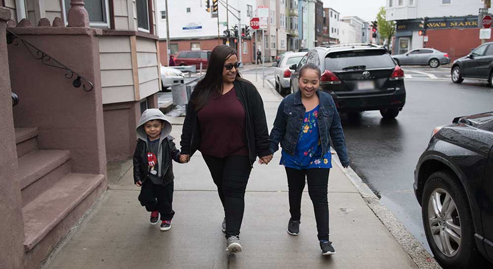Dayanara, her mother, and her little brother walk down the street.