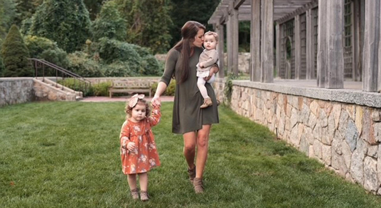 Elisabeth Youngclaus holding her daughters and walking with them outdoors