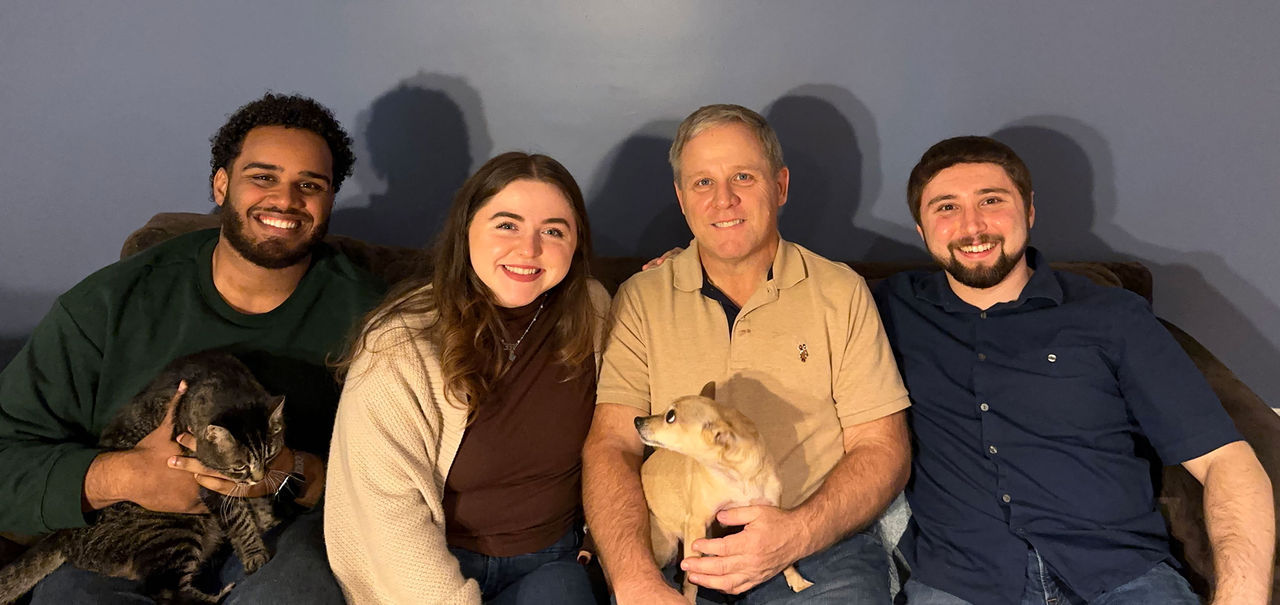 Frank Norton, his daughter and son, his daughter's fiance, their cat, and their little dog together on the couch.