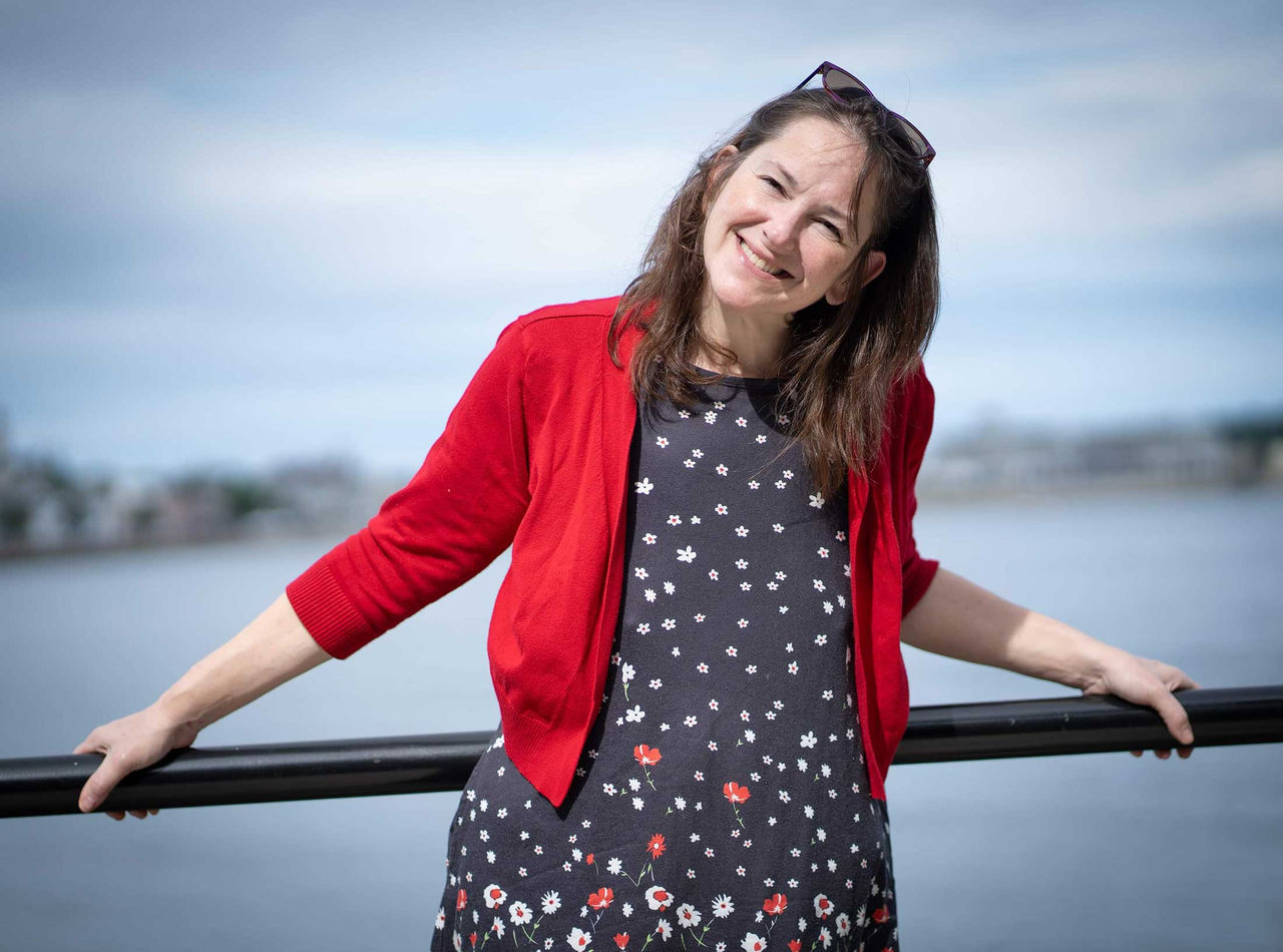 Julie Bice after bariatric surgery, leaning against a railing by the river.