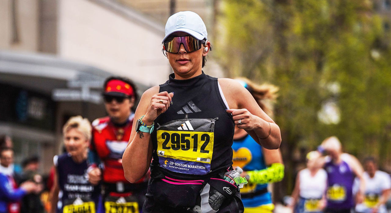 Marathon runner mid-race in athletic gear including a hat and sunglasses.