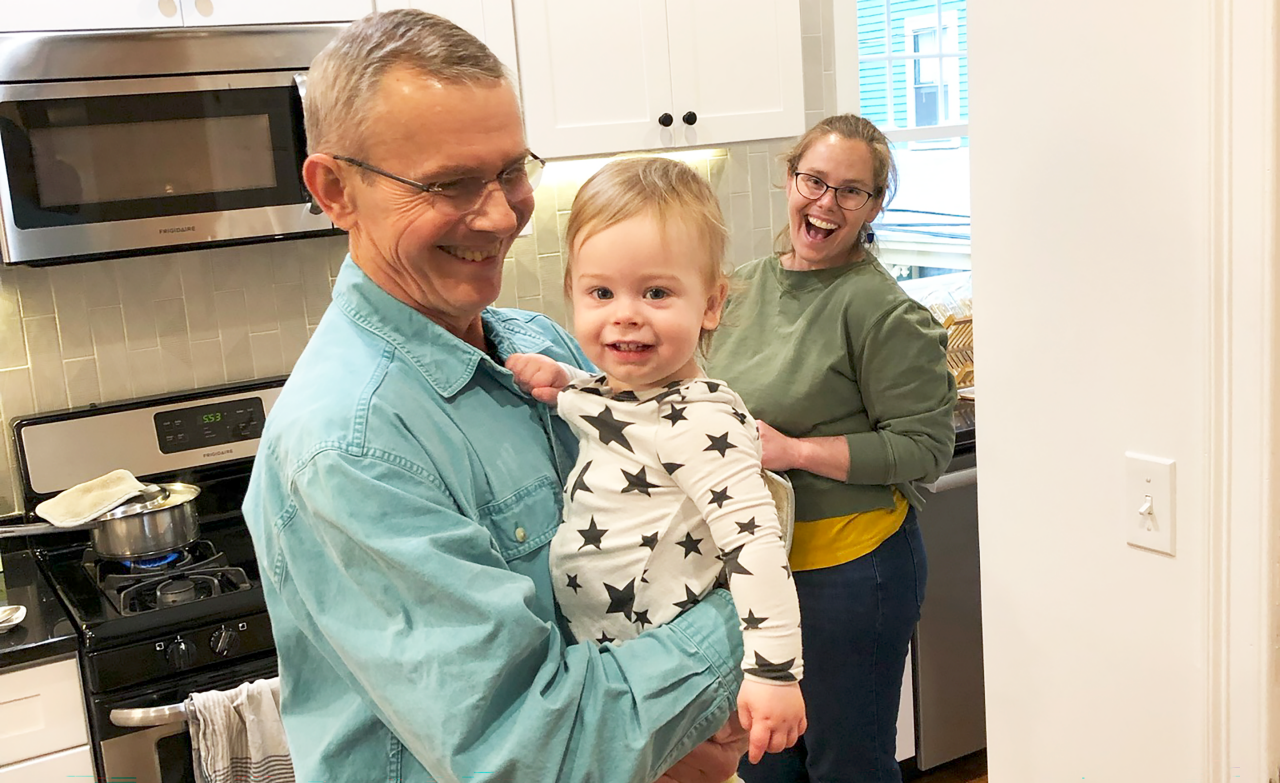 Martin, baby Alden, and Lucy Orloski smiling in the kitchen