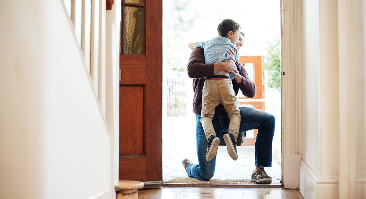 Man hugging small child in doorway of home