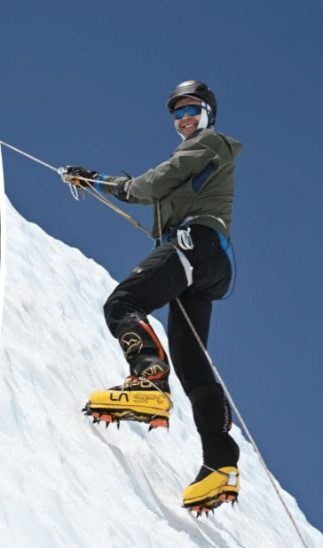 Peter Horsman smiling in climbing gear, rappelling up a cliff.
