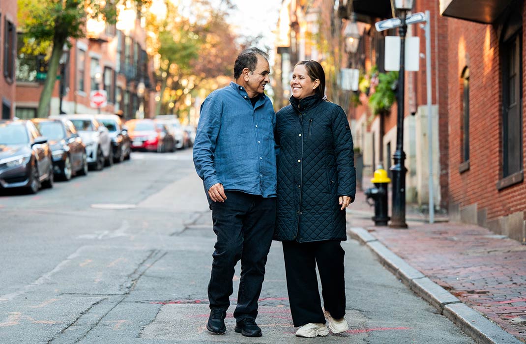 Husband and wife looking and smiling at each other while walking down a street