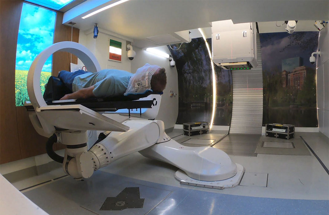 A man lying on an elevated treatment bed for radiation therapy.