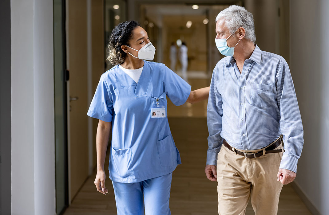 Medical professional and patient talking while walking through hospital hallway