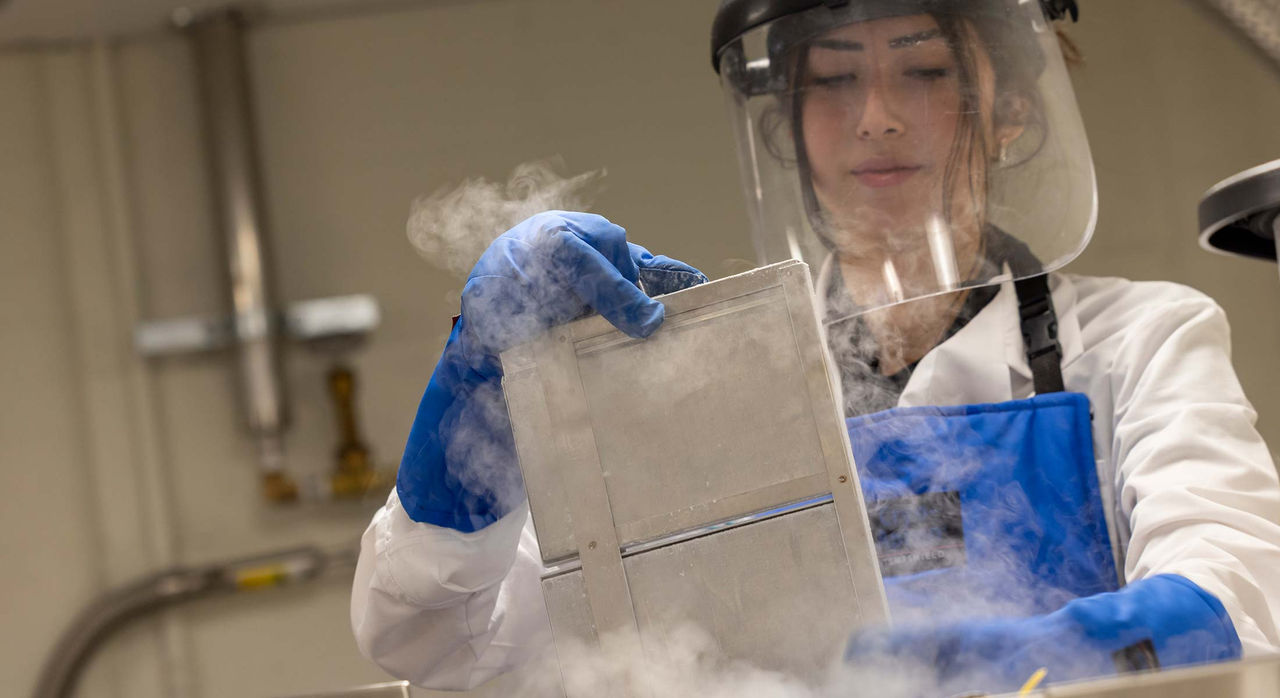 Scientist handling metal tray in laboratory with vapor