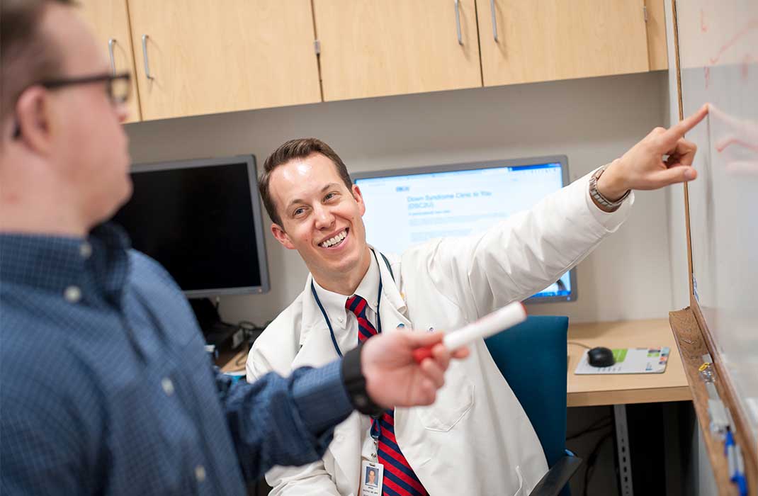 Brian Skotko points something out to a colleague on a whiteboard.