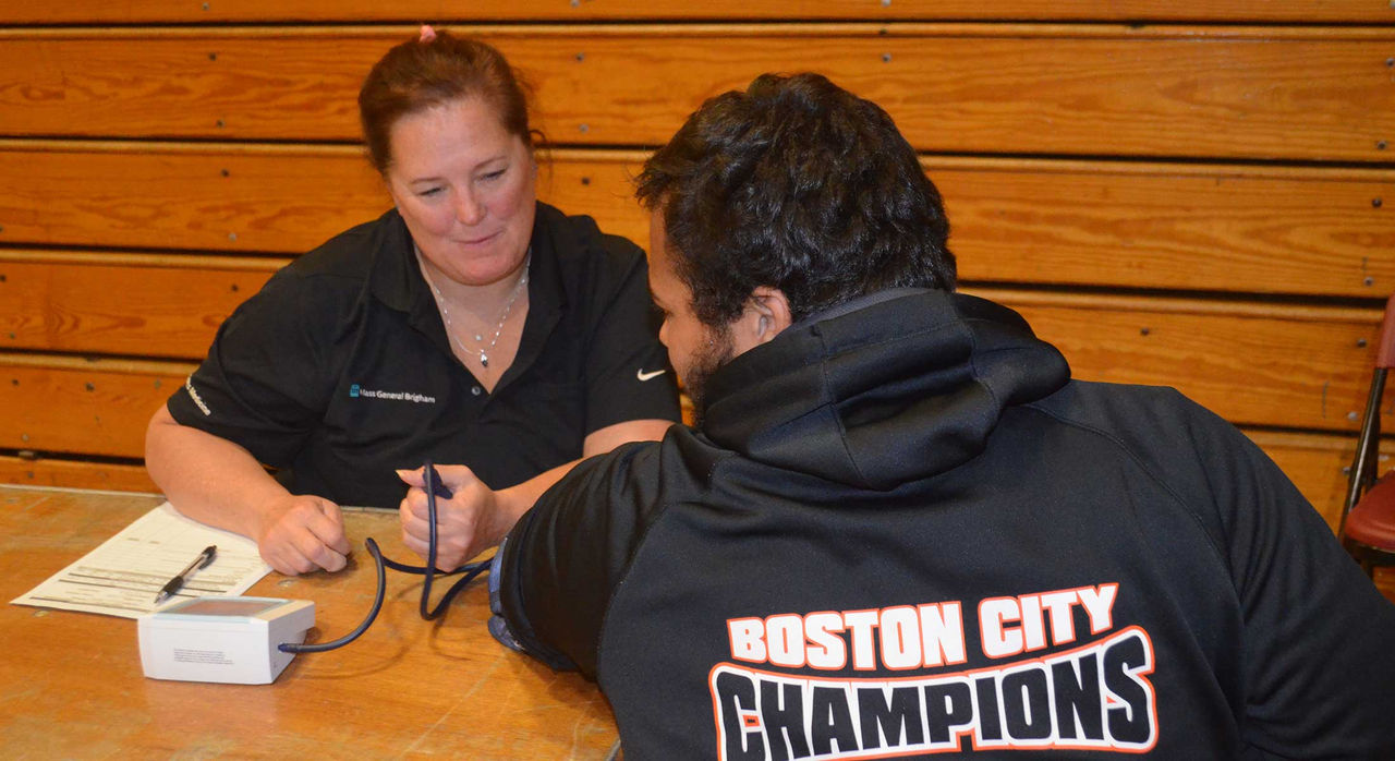 A provider checks a high school athlete's blood pressure.