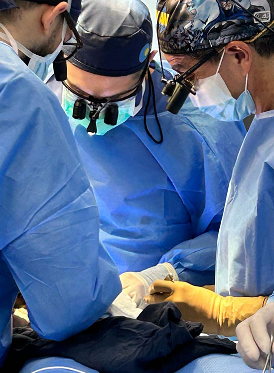 Three physicians in an operating room performing surgery