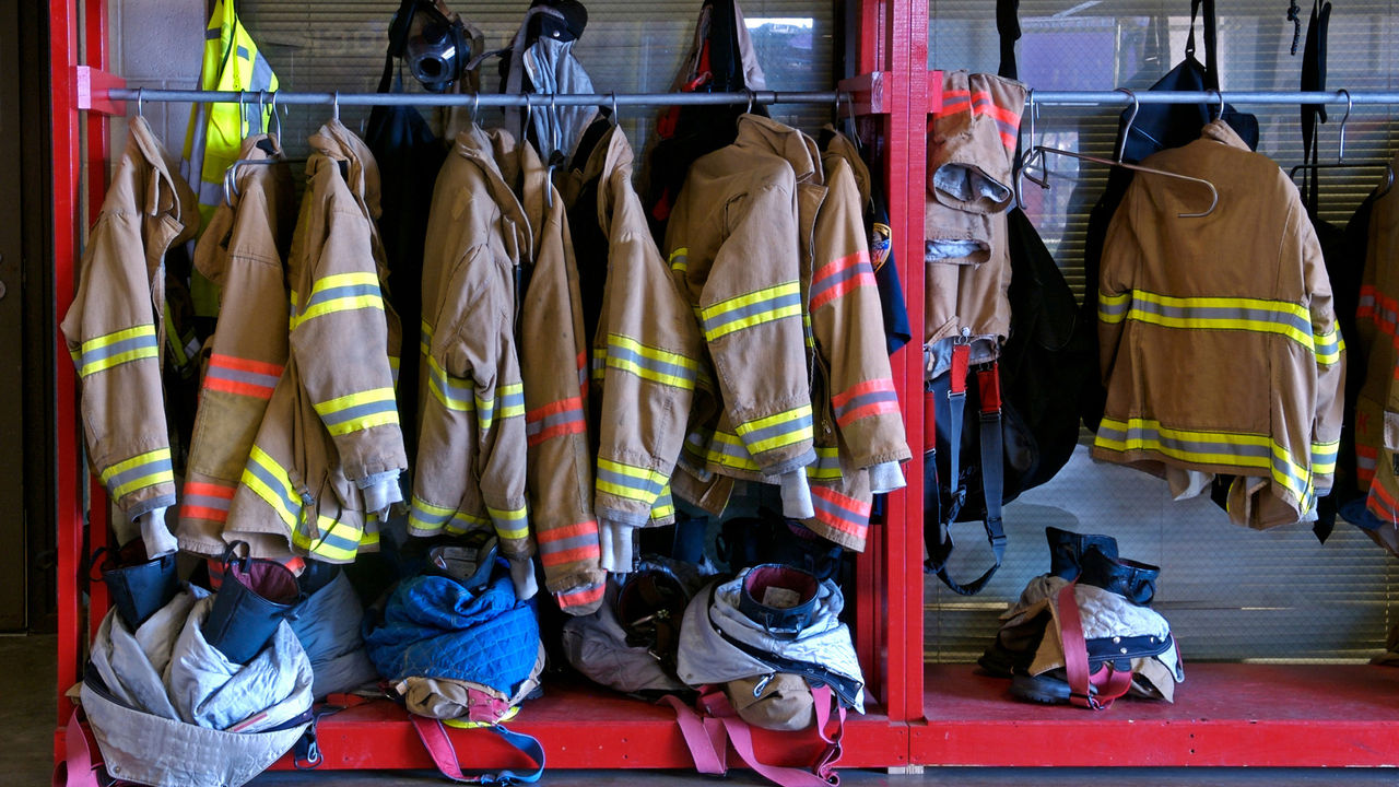 Firefighters’ jackets hang on a rack in a fire station.