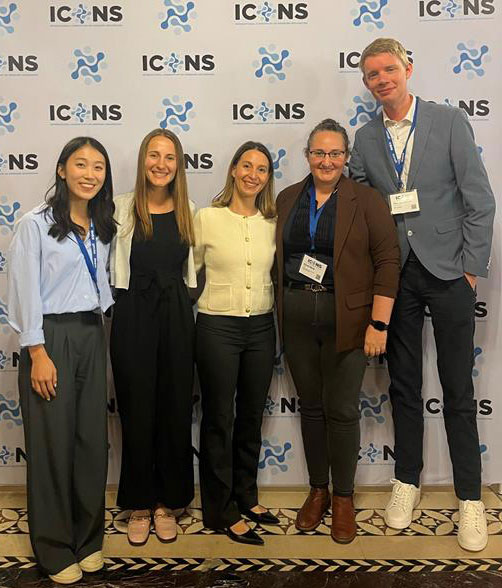 Five team members posing together at a conference.