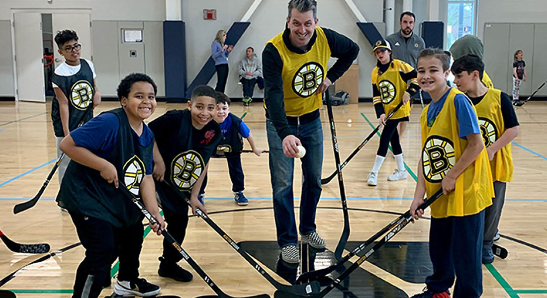 Boston Bruins youth street hockey clinic with children smiling and holding hockey sticks