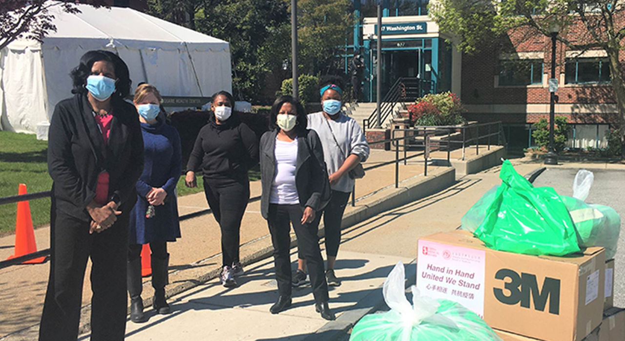 5 individuals at codman square health center with boxes of COVID-19 care kits