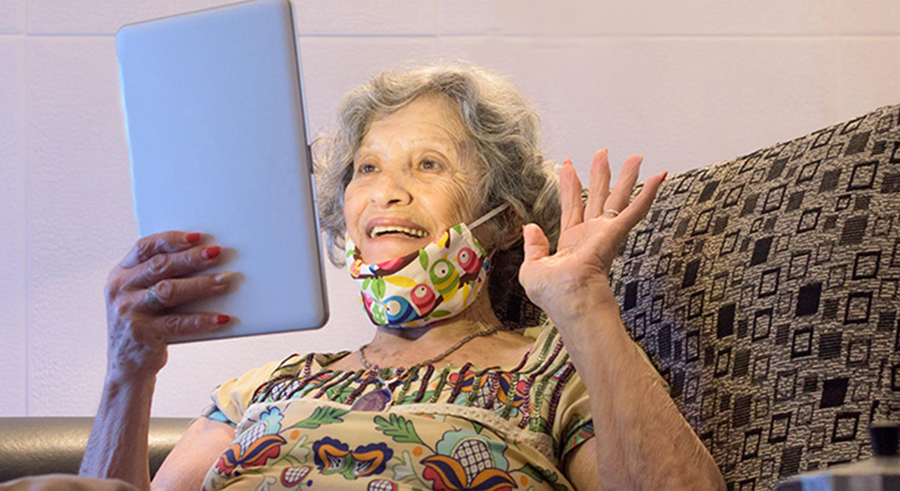 elderly woman smiling and looking at tablet