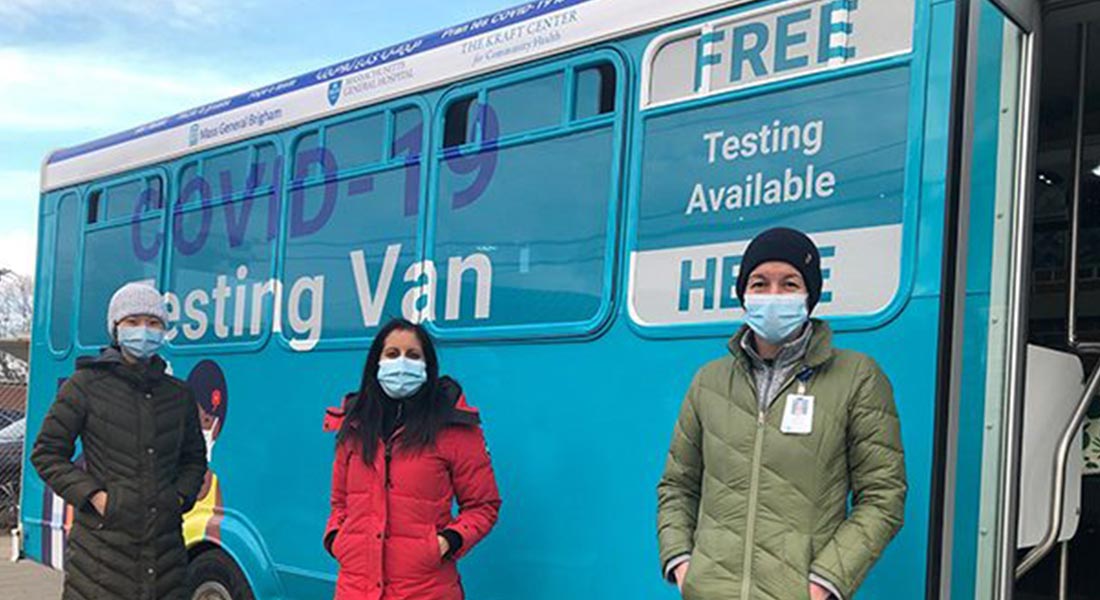 three people standing in front of the COVID-19 testing van