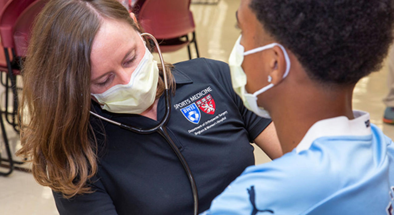 sports medicine clinician with a stethoscope examining a student athlete