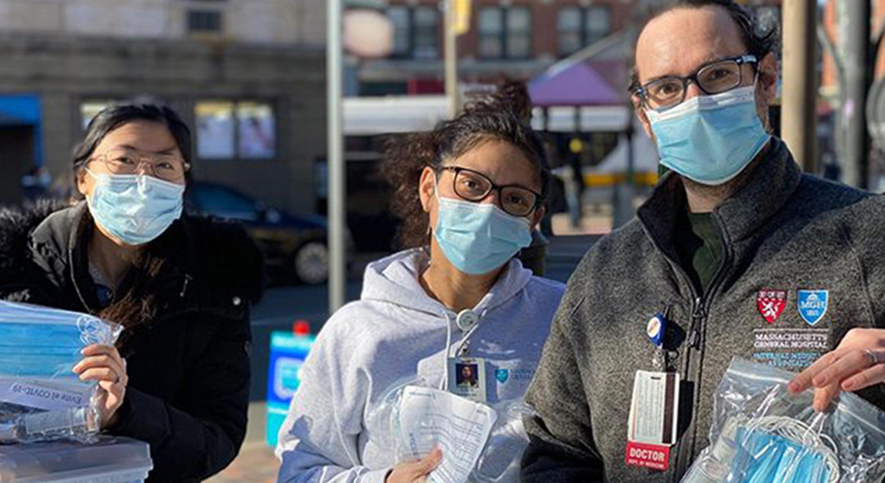 three individuals holding face masks outdoors