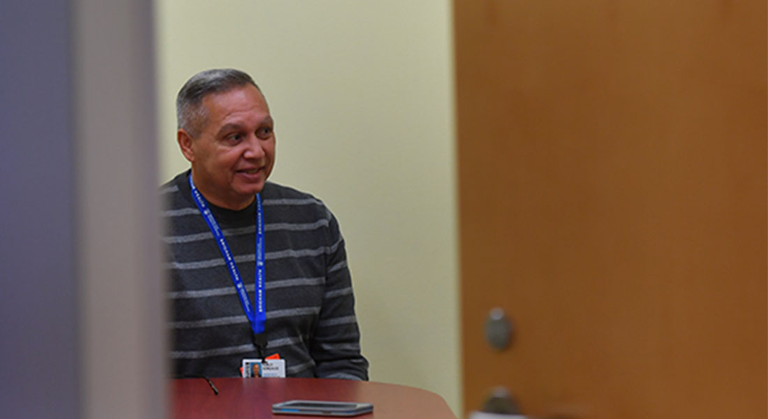 a recovery coach with a lanyard around neck sitting in a room