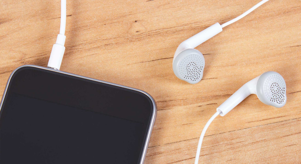 Earbuds lying on a table, connected to a smartphone.