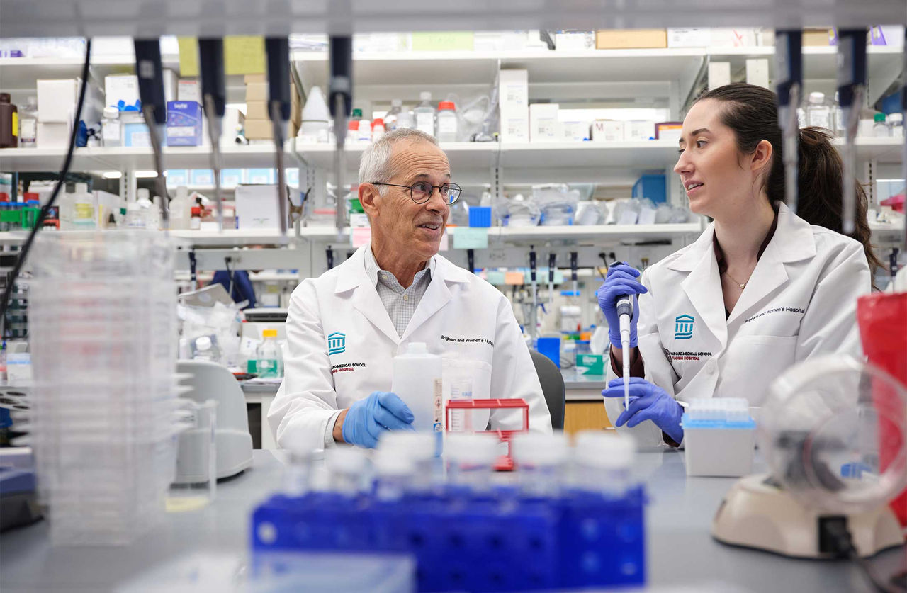 Dr. David Walt talks with research technical assistant Kathryn Lyon while working in a laboratory.