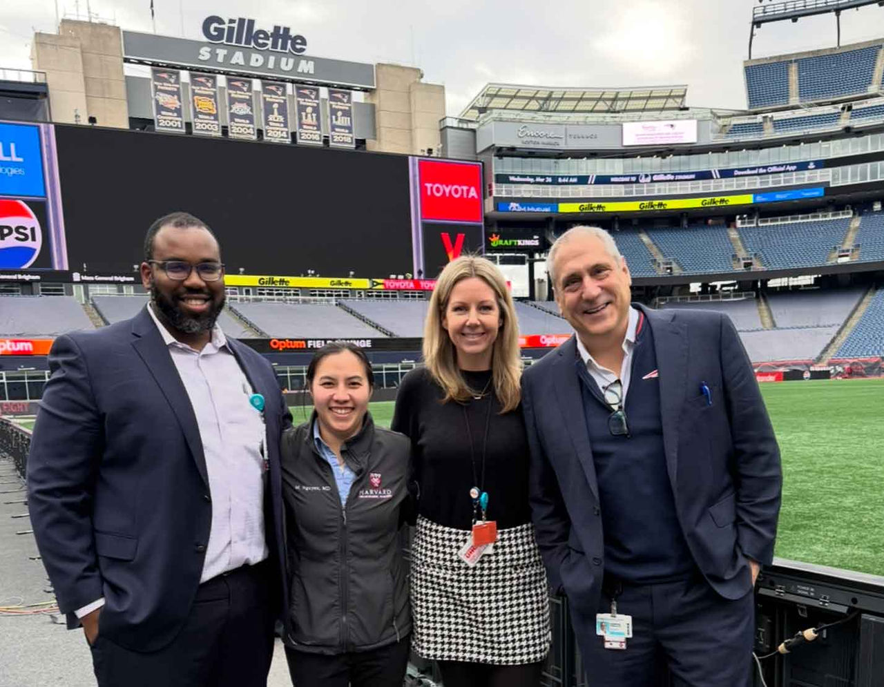 team members posing in front of field at Gillette Stadium
