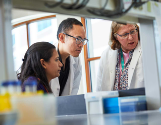 Three researchers in lab looking at monitor 
