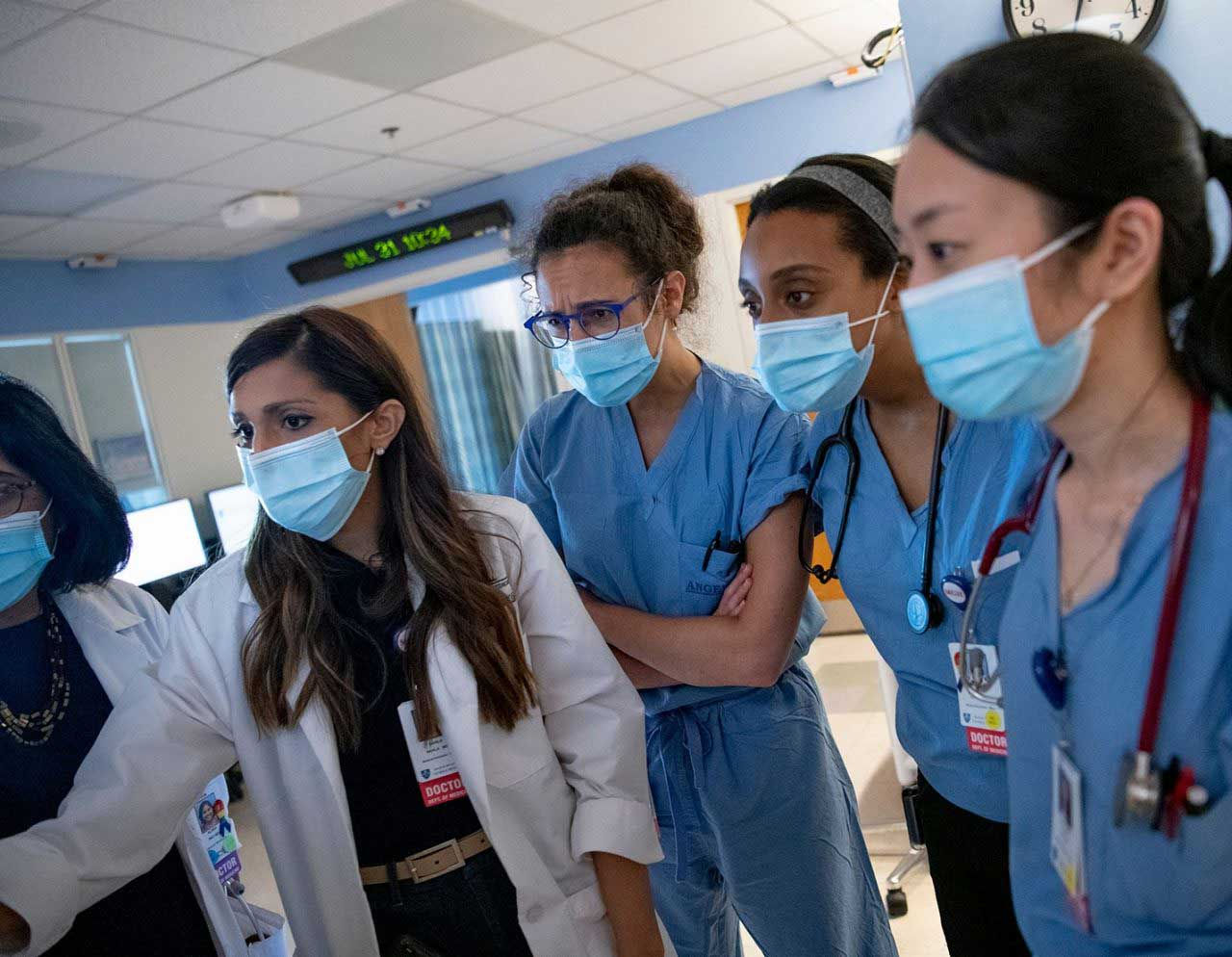 Two female doctors and three female trainees reviewing a patient case.