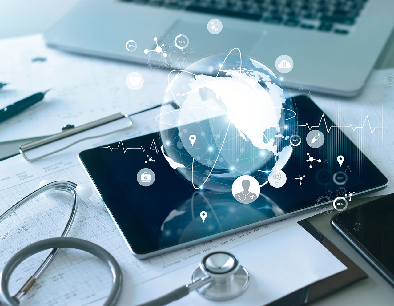 A tablet and a stethoscope on a desk with paperwork with a symbol of a globe