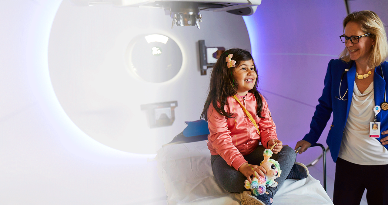 Smiling child and doctor in front of proton beam therapy at Mass General Cancer Center 