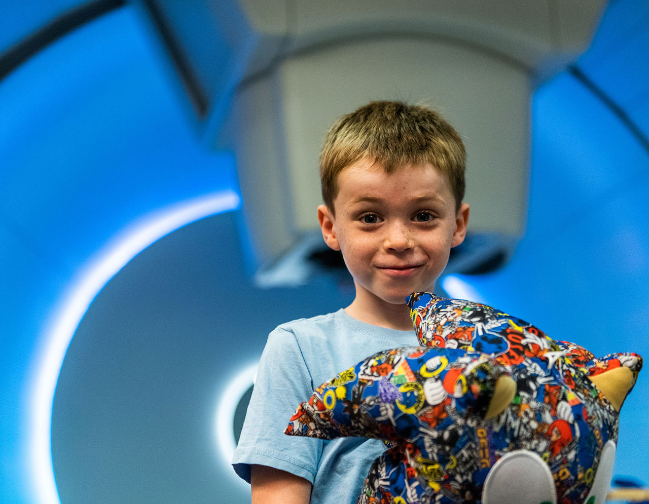 A young boy holding stuffed toy in front of imaging machine 