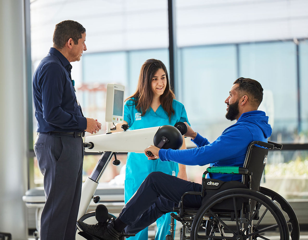 Female provider instructing male patient using rowing machine