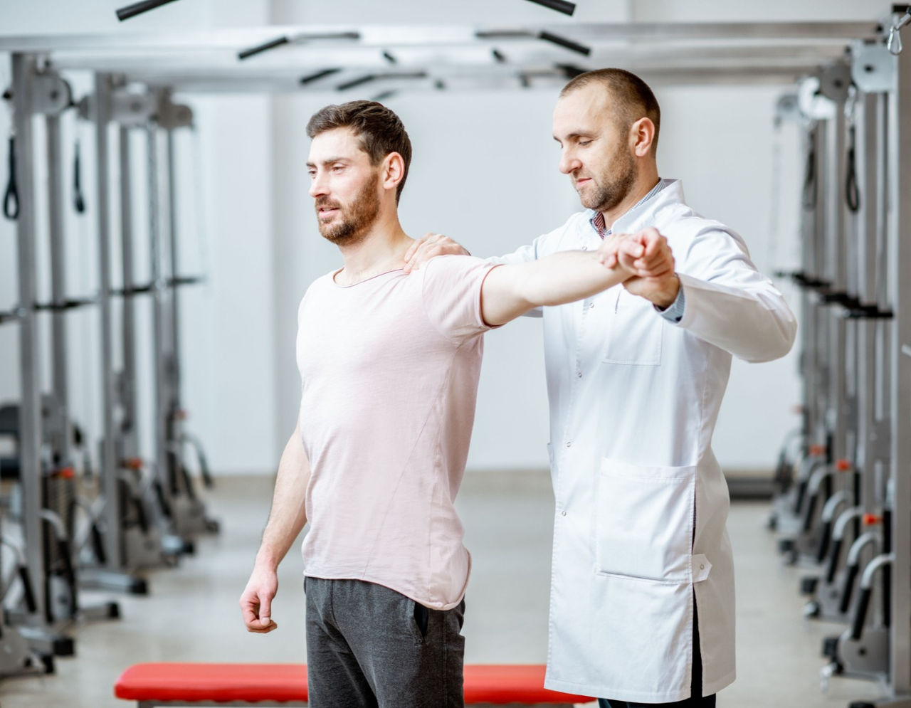 Male provider performing standing exercise with male patient 